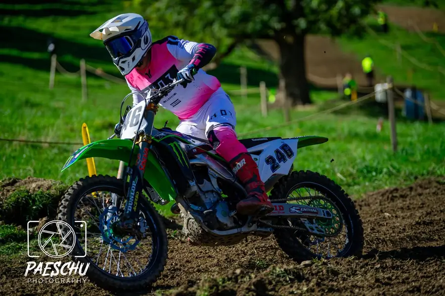 Kenneth auf der grünen Kawasaki mit Startnummer 246 von der Seite, in pink-weisser Kombi auf einer Wiesenstrecke