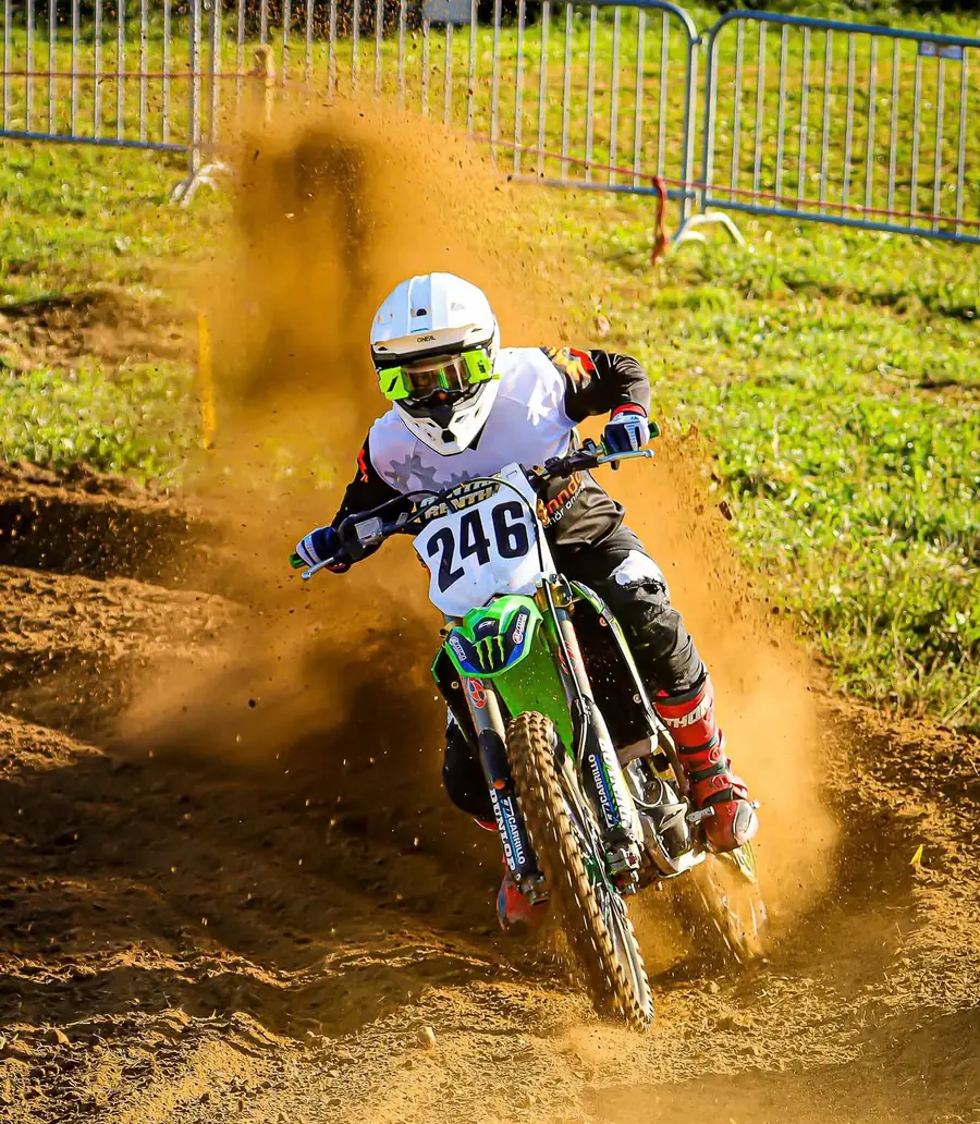 Kenneth auf der grünen Kawasaki mit Startnummer 246 in einer Kurve, hinter ihm eine Wolke aus Erde und Staub